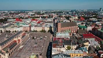 Aerial view of Krakow main market square with historic Cloth Hall , Sukiennice surrounding colorful buildings on sunny day. Cityscape of Krakow in Poland with tourists walking in old town video