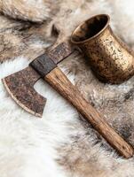 Rustic axe and drinking horn on fur background photo