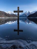 Serene mountain lake with wooden cross reflection photo