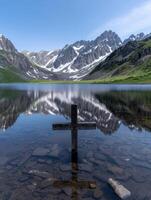 Serene mountain lake with wooden cross reflection photo