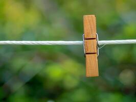 Clothespeg on wire with blurred nature background photo