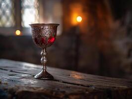 Ornate glass goblet on wooden table with candles photo