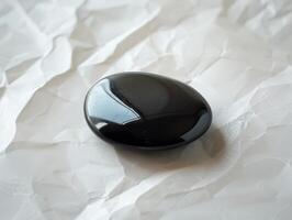 Smooth black stone on crumpled white paper photo