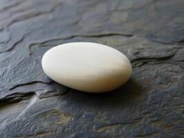 Smooth white stone on slate surface photo