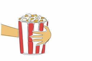 National Popcorn Day. One single line drawing of hand grabbing stripped pop corn paper bucket contain sweet popcorn. Delicious snack to accompany watching movie. Continuous line draw graphic vector