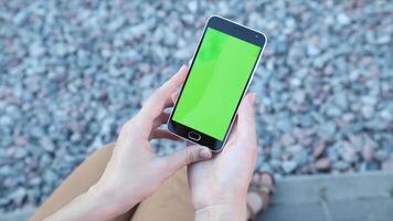 A woman holding a smartphone with a green screen, symbolizing mobile technology and app development. video