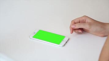 A person is using a green screen on a white phone, ideal for app design, digital content creation, and mobile mockup presentations. video
