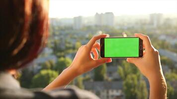 A woman taking a picture with a green screen on her phone, ideal for mobile photography, digital content creation, and app mockup presentations. video