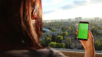 Girl Using Smartphone with Green Screen on Balcony Editable Scene for Creative Projects video