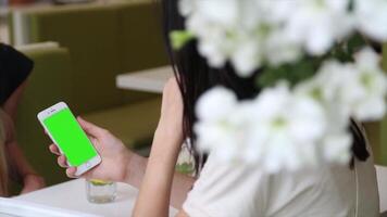 A woman is using a green screen on her phone, ideal for app design, digital content creation, and mobile mockup presentations. video