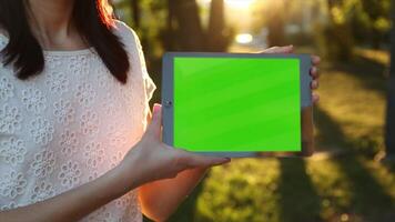 A woman holding a tablet with a green screen, ideal for app design, digital content creation, product mockups, and interactive presentations. video