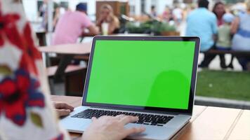A woman using a laptop with a green screen typing on the keyboard and using the touchpad for editing or browsing in a professional and digital workspace environment video