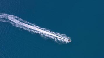 Aerial view of a motor boat forming a circle of waves and bubbles with its engines over the turquoise sea. Drone flight, summer vacation concept, banner. video
