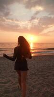 A woman enjoys running on the beach while the sun sets, creating a beautiful moment in time video