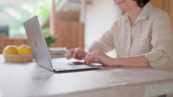 Close-up - Laptop with middle aged woman focused on laptop sitting at desk, thinking or expressing concern, looking at device screen, studying received email, contemplating on work, working online. video