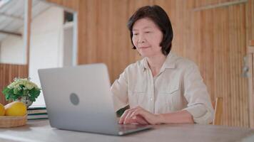Senior woman at home web surfing on laptop computer, looks at device screen, learn received email, ponder on task, doing on-line job, prepare report. Business, tech. video