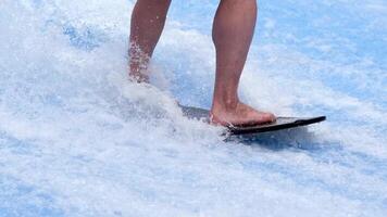 Unrecognized person is surfing on a beautiful artificial wave in a surfing simulator. A sporty guy rides a power surfboard on a blue wave. The concept of sports, summer fun and relaxation. video