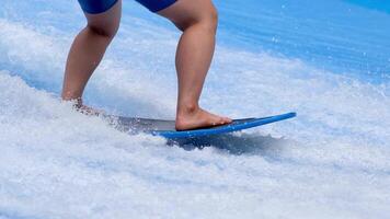 Unrecognized person is surfing on a beautiful artificial wave in a surfing simulator. A sporty guy rides a power surfboard on a blue wave. The concept of sports, summer fun and relaxation. video