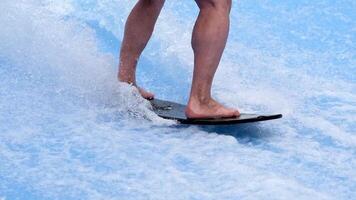Unrecognized person is surfing on a beautiful artificial wave in a surfing simulator. A sporty guy rides a power surfboard on a blue wave. The concept of sports, summer fun and relaxation. video