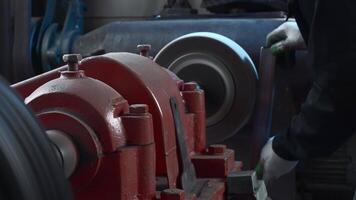 Close up shot of craftsman working on grinding machine with polishing disk while smoothing metal workpiece. Creative. Production process at factory, concept of manufacturing, industrial and technology video