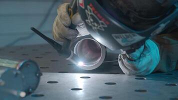 Engineer in a protective mask makes welding of metal pipe. Creative. Face of welder is close to sparks. video