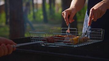 Man turns meat on grill. Stock footage. Close-up of man turning over pieces of meat on grill. Turning meat on grill for roasting on sunny summer day video