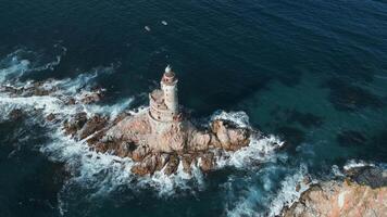 Top view of beautiful rocky cape with lighthouse. Clip. Cinematic landscape of rocky cape and lighthouse with sea waves. Rocky cape with abandoned lighthouse in sea on sunny summer day video