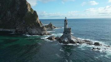 Top view of rocks in sea with abandoned lighthouse. Clip. Beautiful view of old lighthouse and rocky cape in sea. Landscape lighthouse on rocky cape in ocean on sunny summer day video