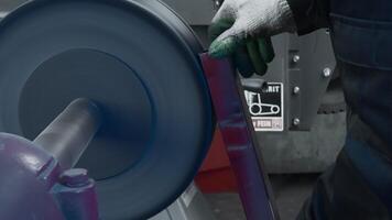 Worker polishes metal part on circular machine. Creative. Circular machine for polishing metal parts and beams. Worker polishes steel part at factory video