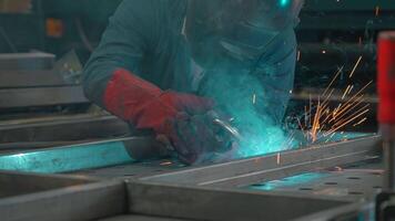 Man in mask works with welding metal structures at factory. Creative. Welder in equipment works at industrial plant. Worker with welding and welding sparks from metal video