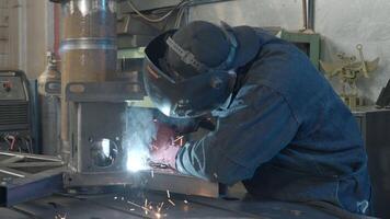 Welder in workshop repairs structure with sparks. Creative. Work of welder in industrial production. Welder in mask with welding sparks repairs structure in production video