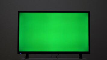 Close-up of TV screen with green background. Concept. Plasma TV screen with green screen. Modern TV on bedside table with green screen for insertion in house video