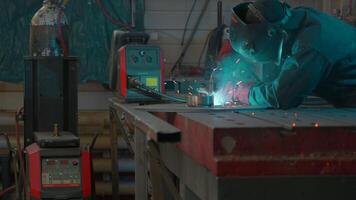 Welder in mask and working uniform working on metal structure. Creative. Man in mask with welding and sparks from working with metal. Working with welding at industrial plant video