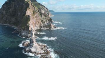 Top view of rocks in sea with abandoned lighthouse. Clip. Beautiful view of old lighthouse and rocky cape in sea. Landscape lighthouse on rocky cape in ocean on sunny summer day video