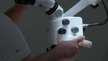 Surgeon looking into the microscope at the operating room. Action. Doctor using microscope. video