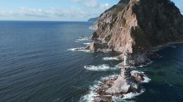 Top view of rocky cape landscape and lighthouse in sea. Clip. Fabulous landscape of rocky cape of island with abandoned lighthouse. Seascape with rocky cape and lighthouse on sunny day video