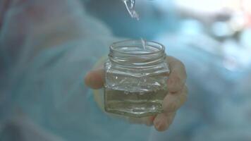 Pouring sterile liquid into the small container in the operating room. Action. Team of medical workers. video