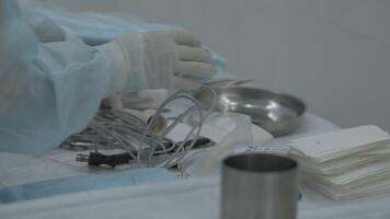 A table of medical tools are placed upon a table in preparation for surgery. Stock footage. Nurse putting instruments on the table. video