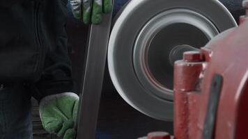 Worker polishes metal part on machine. Creative. Polished metal part is carried out on rotating machine. Worker polishes steel part at factory video