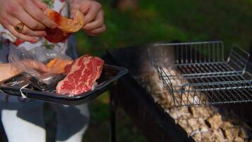 Close-up of man grilling pieces of red meat. Stock footage. Man cooks two pieces of beef or pork on grill. Man cooks meat on grill in nature in summer video
