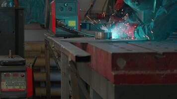 Welder in mask and working uniform working on metal structure. Creative. Man in mask with welding and sparks from working with metal. Working with welding at industrial plant video