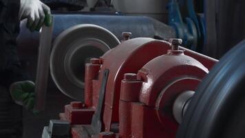 Close up shot of craftsman working on grinding machine with polishing disk while smoothing metal workpiece. Creative. Production process at factory, concept of manufacturing, industrial and technology video
