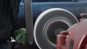 Worker polishes metal part on machine. Creative. Polished metal part is carried out on rotating machine. Worker polishes steel part at factory video