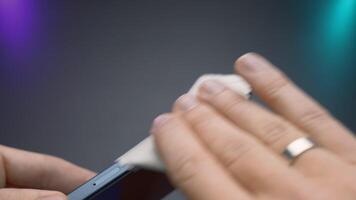 Close-up of man wiping new phone. Action. Person wipes new phone with special cloth. Man wipes case of new phone with rag video