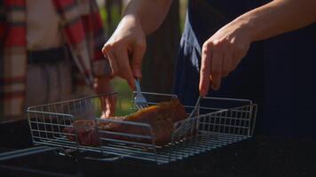 Man turns meat on grill. Stock footage. Close-up of man turning over pieces of meat on grill. Turning meat on grill for roasting on sunny summer day video