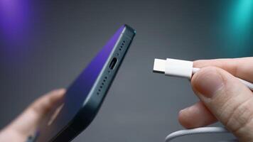 Close-up of type C wire for charging phone. Action. Type-C connector for charging phone on isolated ofn. New wire type C and included for phone video