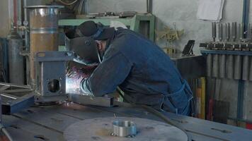 Welder in workshop repairs structure with sparks. Creative. Work of welder in industrial production. Welder in mask with welding sparks repairs structure in production video