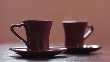 Close up of two small espresso cups with raising steam. Concept. Stylish ceramics, heart shaped handle. video