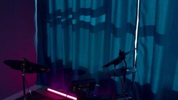 Drum kit in the empty room with neon lighting. Media. Musical instrument in a recording studio. video