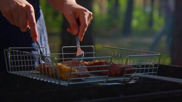 Man turns meat on grill. Stock footage. Close-up of man turning over pieces of meat on grill. Turning meat on grill for roasting on sunny summer day video